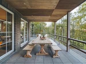 una mesa de madera en un porche cubierto con bancos en Beautiful villa in Durbuy, en Durbuy