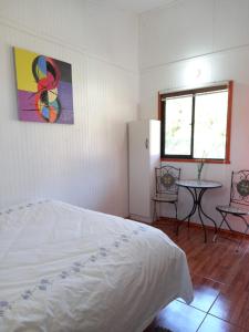 a bedroom with a bed and a table and a window at Alojamiento Ximena in Coñaripe