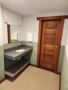 baño con lavabo y puerta de madera en Apartamentos da Rota en Domingos Martins