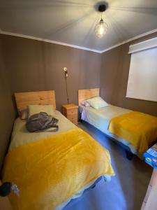 two beds in a room with yellow sheets at Cabañas Sol de Vicuña in Vicuña