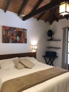 a bedroom with a bed and a painting on the wall at Casinha Astral - Praia da Ferrugem in Garopaba
