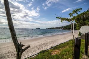 uma praia com uma cerca e o oceano em Jurerê - Direto na Praia em Florianópolis