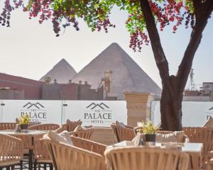 eine Reihe von Tischen und Stühlen mit den Pyramiden im Hintergrund in der Unterkunft The Palace Pyramids Hotel in Kairo