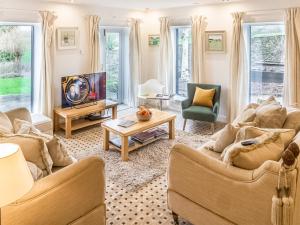 a living room with two couches and a tv at The Old Pool House in Charlton Abbots