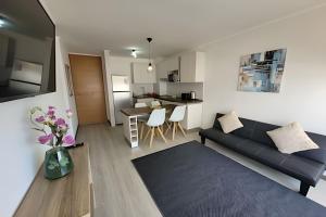 ein Wohnzimmer mit einem schwarzen Sofa und einer Küche in der Unterkunft Condominio Pacífico 3100 in La Serena