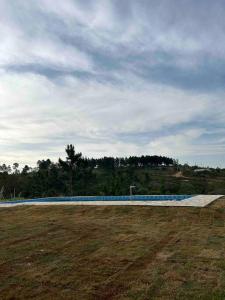a swimming pool in a field with a cloudy sky at Chácara Ohana in Mairinque