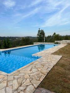 a swimming pool with blue water and a stone pathway at Chácara Ohana in Mairinque