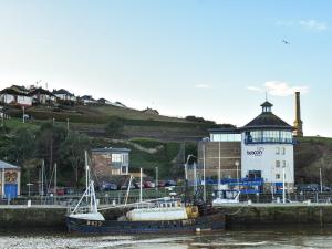 a boat docked in the water next to a lighthouse at Hugh Cottage in Whitehaven