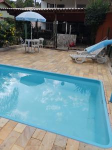 uma grande piscina azul com uma mesa e um guarda-sol em Sitio Cantinho da Alegria em Confins