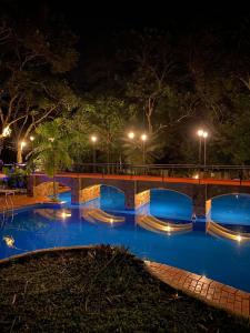 a swimming pool at night with a bridge and lights at Hotel Cabañas del Leñador in Puerto Iguazú