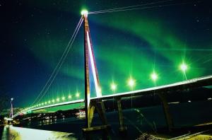 een brug met het noorderlicht in de lucht bij Sentralt og hjemmekoselig in Narvik