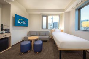 a hotel room with a bed and a couch at Hop Inn Tokyo Asakusa in Tokyo