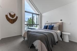 a white bedroom with a bed and a large window at Urban Nest - Entire Townhouse and Free Parking in Christchurch