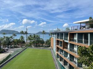 an apartment building with a lawn in front of the water at The Nature Phuket - SHA Extra Plus in Patong Beach