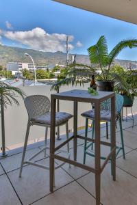 mesa y sillas en la parte superior de un balcón en Charmant Appartement Topaze en Papeete