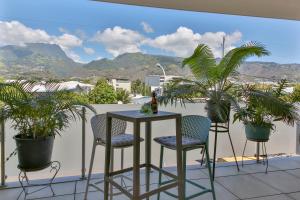 una mesa y sillas en un balcón con plantas en Charmant Appartement Topaze en Papeete