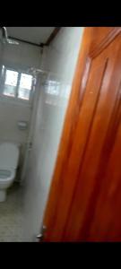 a bathroom with a toilet and a wooden door at Residence Mindja in Yaoundé