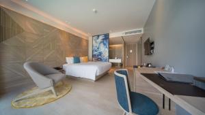 a bedroom with a bed and a desk with a chair at The Nature Phuket - SHA Extra Plus in Patong Beach