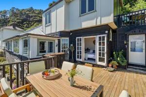 a house with a wooden deck with a table and chairs at Seaglass Cottage in Lower Hutt
