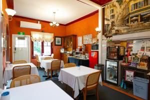 a restaurant with white tables and chairs and orange walls at KUBBA ROONGA GUESTHOUSE - Boutique Luxury Peaceful Stay & Gardens - Bed & Breakfast in Blackheath