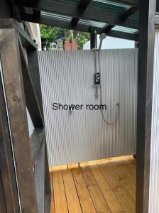 una puerta a un baño con ducha y suelo de madera en Hosts on the Coast - Rocco's Retreat, en Kuaotunu