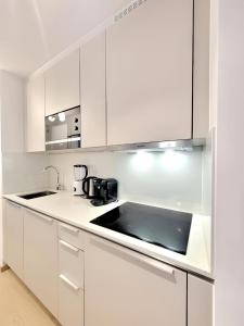 una cocina blanca con armarios blancos y fregadero en GRAND SABLON Stylish Brussels City Center Apartment, en Bruselas