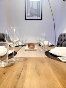 una mesa de madera con copas de vino y platos en ella en GRAND SABLON Stylish Brussels City Center Apartment, en Bruselas