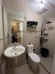y baño con lavabo, aseo y espejo. en Apartment in Batasan Hills in QC, en Manila