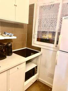 cocina con armarios blancos y nevera blanca en appartement agréable tout confort Entièrement Meublé, en Aubervilliers