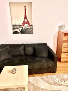 un divano nero in un soggiorno con la torre Eiffel di appartement agréable tout confort Entièrement Meublé ad Aubervilliers