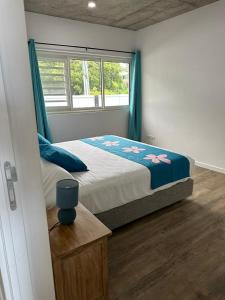 1 dormitorio con 1 cama con cortinas azules y ventana en Pension Irivai, Appartement RAVA 1 chambre bord de mer, en Uturoa