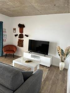 a living room with a couch and a flat screen tv at Pension Irivai, Appartement RAVA 1 chambre bord de mer in Uturoa
