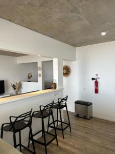 una habitación con 4 sillas negras y un mostrador en Pension Irivai, Appartement RAVA 1 chambre bord de mer, en Uturoa