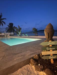 a resort swimming pool with a statue in the foreground at Pension Irivai, Appartement RAVA 1 chambre bord de mer in Uturoa