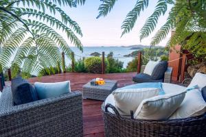 un patio con sillas de mimbre y una mesa con vistas en The Retreat - Luxury Hillside villa at Te Ngaere Bay en Kaeo