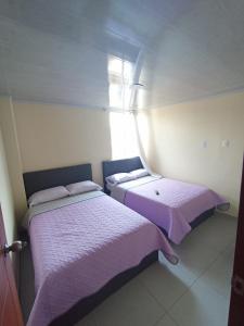 - 2 lits dans une chambre avec des draps violets et une fenêtre dans l'établissement HOTEL EL GRAN CASINO ESMERALDA, à Barbosa