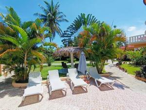 un grupo de sillas, paraguas y palmeras en Luxury Villa Classic style - 7 min. from the beach, en San Felipe de Puerto Plata