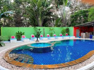 uma grande piscina com cadeiras azuis e vermelhas à volta em Kamrai Resort em Ko Chang