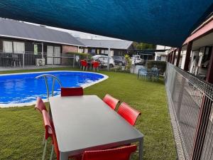 uma mesa e cadeiras ao lado de uma piscina em ASURE Kapiti Court Motel em Paraparaumu Beach