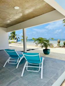 - deux chaises et une table sur la plage dans l'établissement Pension Irivai appartement PUATOU 1 chambre bord de mer, à Uturoa