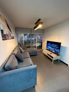 a living room with a couch and a flat screen tv at Departamento a pasos de PLAYA BRAVA! Cavancha in Iquique