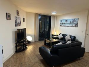 a living room with a black couch and a television at Discover Comfort and Style - Your Elegant Stay Offers a 2-Bedroom Haven with Free Parking and Coffee! in Birmingham