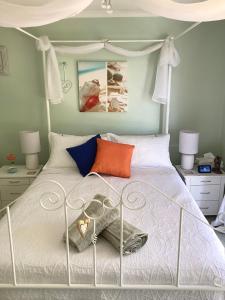 um quarto com uma cama branca e almofadas coloridas em Azalea Bed and Breakfast Hideaway em Tura Beach