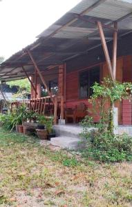 a house with a porch with plants in front of it at Adinda house อดินดาเฮาส์ in Chiang Dao