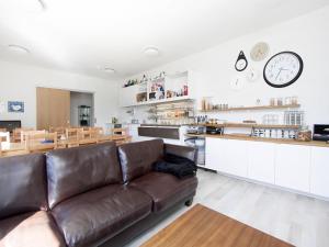 a living room with a brown leather couch and a kitchen at KEF Guesthouse by Keflavík airport in Keflavík