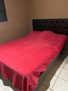 ein Bett mit einer roten Decke darüber in der Unterkunft Casa para temporada, Guilherme. in Vargem Bonita