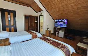 a hotel room with two beds and a flat screen tv at Villa Pink House in Da Lat