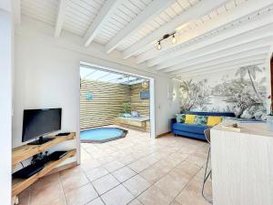 ein Wohnzimmer mit einem blauen Sofa und einem TV in der Unterkunft Terrathely in Le Moule