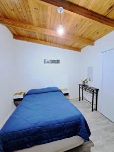 a bedroom with a blue bed and a wooden ceiling at La Guanaca in Perito Moreno