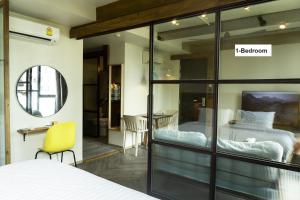 a bedroom with two beds and a yellow chair at karaarom hotel in Bangkok